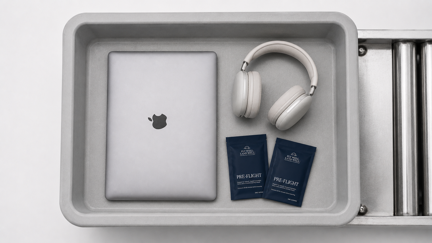 Airport tray image with fly well land well products, laptop, and headphones